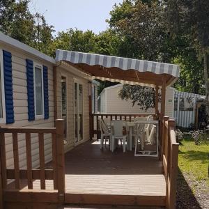 a deck with a pergola and a table and chairs at MOBILHOME Soulac in Soulac-sur-Mer