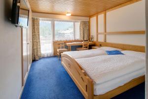 a bedroom with two beds and a desk and a television at Hotel Parnass in Zermatt