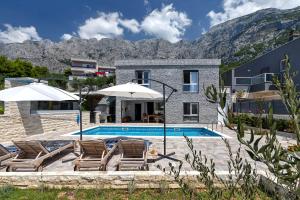 a house with a swimming pool with chairs and umbrellas at Villa Infinite Joy in Makarska