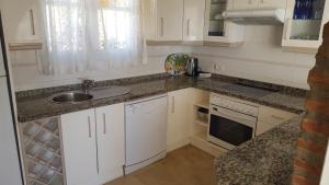 a kitchen with white cabinets and a sink at El Capistrano Sur in Nerja