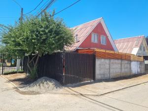 a red house with a fence and a tree at Apartamento KATHY in Talca