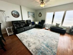 a living room with a black leather couch and a rug at Sand Dollar 3-304 in Saint Augustine