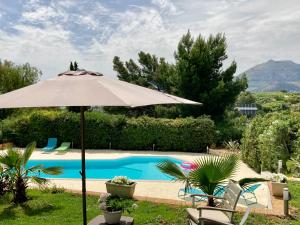 an umbrella and chairs next to a swimming pool at Loft - Villa Flore apartments in villa in Casteldaccia