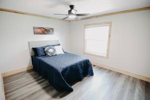 a bedroom with a bed with a blue blanket and a window at The Ranch in Elizabethtown