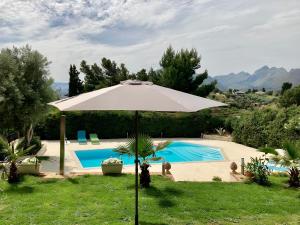 an umbrella in the grass next to a swimming pool at Loft - Villa Flore apartments in villa in Casteldaccia