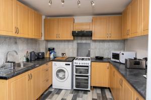 a kitchen with wooden cabinets and a washer and dryer at HouseSleep14-FreeP-Garden-Bbq-Patio-PoolTable in London +28 photos