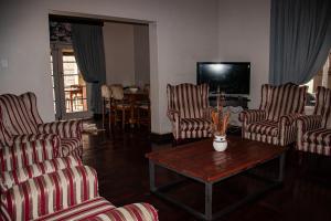 a living room with chairs and a table and a tv at Colenso Lodge B&B in Colenso