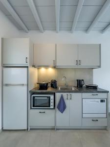a kitchen with white cabinets and a sink at ANETON Residences in Karavostasi