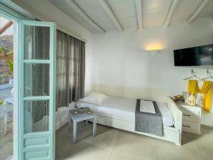 a bedroom with a white bed and a tv at ANETON Residences in Karavostasi