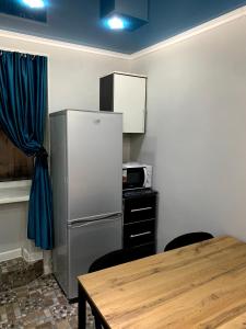 a kitchen with a refrigerator and a table with chairs at Safar in Karakol