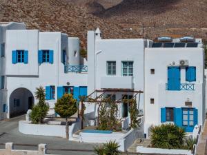 a white building with blue windows and plants at ANETON Residences in Karavostasi