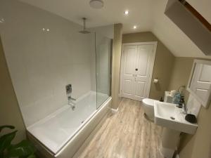 a bathroom with a shower tub and a sink at Neptune House The Bay Filey Home Sweet Holiday Homes with car ev point in Filey +11 photos