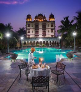a woman sitting at a table in front of a hotel at Jagat Palace in Pushkar