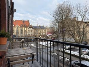 un balcón con un banco de madera en una calle de la ciudad en Apartment Zamulkowa Katowice, en Katowice