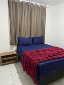una camera da letto con un letto con cuscini blu e una finestra di Apartamento Completo - Piscina, Pet Friendly, Academia No coração da Cidade a Feira de Santana