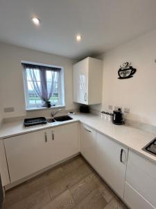 a kitchen with white cabinets and a sink and a window at Radbourne House - Spacious 2 Bed, Home from Home in Derby in Derby