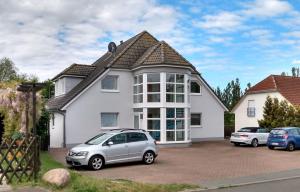 a white house with two cars parked in a driveway at Ferienwohnung-Moorberg-mit-schoener-Terrasse-in-ruhiger-Lage in Dreschvitz