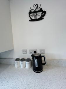 a coffee pot and three cups on a kitchen counter at Radbourne House - Spacious 2 Bed, Home from Home in Derby in Derby