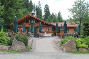 ein Gebäude mit Tischen und Sonnenschirmen davor in der Unterkunft Ferienhaus Seefried in Baiersbronn
