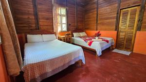 a bedroom with two beds in a room with wooden walls at Cabañas Yax-ha in Arroyo Agua Azul