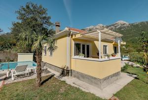 a yellow house with a pool and a palm tree at Villa Relax in Herceg-Novi