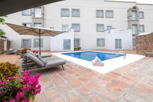 a patio with a swimming pool and an umbrella at Hotel Suites México Plaza León Campestre in León