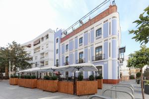 a white building with tables and umbrellas in front of it at La Casa Azul Boutique Hotel in Andújar