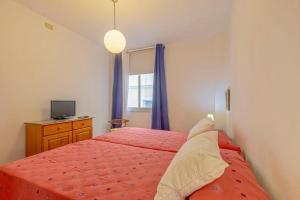 Un dormitorio con una cama roja y un televisor. en Casa Leila, en Puerto Naos