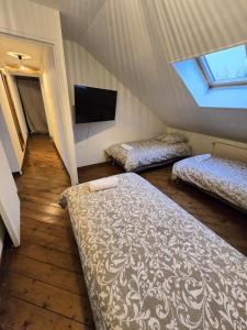 a attic room with two beds and a flat screen tv at Appartement Spacieux 4 Chambres in Flers-en-Escribeus +20 photos