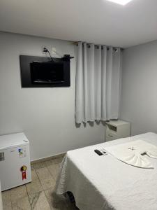 a room with a bed and a tv on the wall at Hotel Vitrine in Goiânia