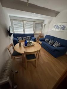 a living room with a table and a blue couch at apartamento sierra nevada pegado telesilla in Sierra Nevada