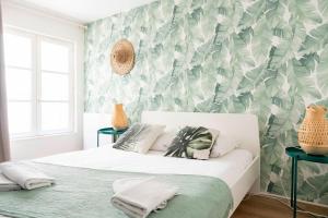 a bedroom with a white bed with a tropical wallpaper at Grand appartement Rue Caponiere - Centre de Caen à pied in Caen