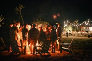 a group of people standing around a fire at night at Escondite: Modern Desert Hideout w Pool + Spa in Landers +38 photos