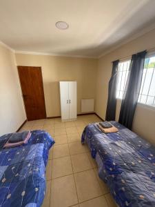 a bedroom with two beds and a door and windows at Departamento en Ramallo in Ramallo