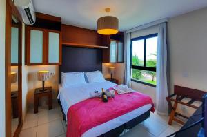 a bedroom with a large bed with a red blanket at VG Sun Cumbuco Nascente Vista Mar 4 Pessoas in Paracumbuca +24 photos