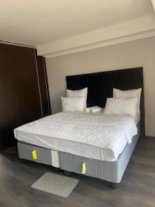 une chambre avec un grand lit avec des draps et des oreillers blancs dans l'établissement Silent corner guest house, à Roodepoort