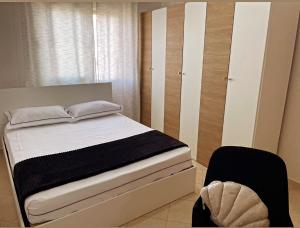 een slaapkamer met een bed en een zwarte stoel bij Bliss Home in Vlorë