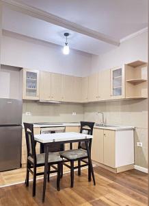 een keuken met een tafel, stoelen en een koelkast bij Bliss Home in Vlorë