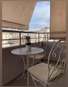 een tafel en stoelen op een balkon met een raam bij Bliss Home in Vlorë
