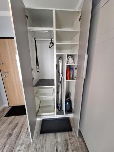 グダニスクにあるLive like a local 5th FLOOR apartmentの白い棚とドア付きのウォークインクローゼット