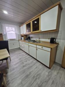 a kitchen with white cabinets and a sink and a table at Ferienwohnung - Stern - in Rollshausen