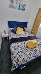 a bed with a blue and yellow comforter on it at Cosy Retreat Your Home Away in Portsmouth +10 photos