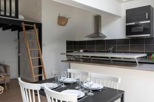 eine Küche mit einem schwarzen Tisch und weißen Stühlen sowie einer Küche in der Unterkunft Appartement proche Place Saint-Sauveur in Caen + 9 Fotos