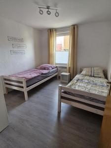 two beds in a room with a window at Ferienwohnung - Stern - in Rollshausen