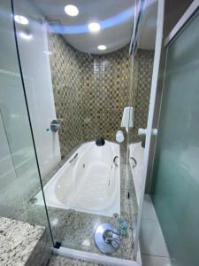 a bath tub in a bathroom with a glass door at AJ TERMAS HOTEL IRAÍ in Iraí