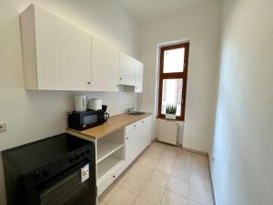 莱比锡Zu Fuß ins Zentrum, nahe Arena的厨房配有白色橱柜和黑色微波炉