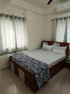 a large bed in a bedroom with blue curtains at 2BHK AC Service Apartment 204 Bhugaon in Pune