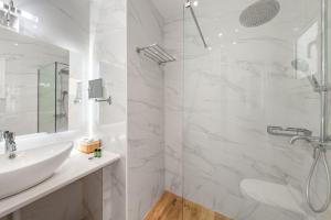 a white bathroom with a sink and a shower at Lido Sofia Apartments in Agios Gordios