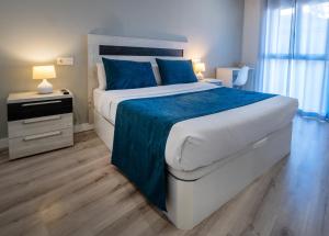 sypialnia z dużym łóżkiem i niebieskimi poduszkami w obiekcie Apartamentos Aranda w mieście Aranda de Duero
