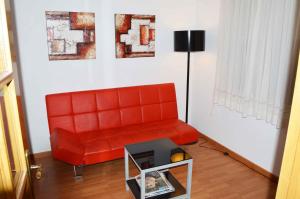 a red couch in a living room with a table at Pensión Residencia Fornos in Santiago de Compostela